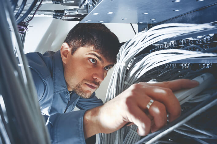 IT apprentice connecting network cables to a network hub